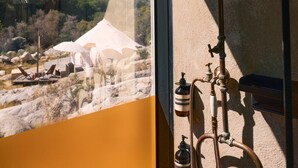 A bathroom with a shower, visible pipes, and a window overlooking a mountainous area. - Paradise Ranch Inn - Mindful Tent (Three Rivers)