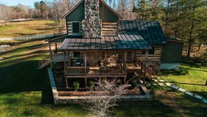 A log cabin with a porch, a stone chimney, and a fenced yard. - Rustic Luxury Near Charlottesville/Montpelier/Wineries /A Historic Cabin Retreat (Somerset)