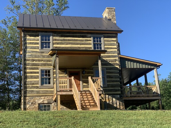 A log cabin with a stone foundation, a covered porch, and a staircase leading to the entrance. - Rustic Luxury Near Charlottesville/Montpelier/Wineries /A Historic Cabin Retreat (Somerset)