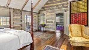 A log cabin room with a four-poster bed, wooden floors, and a large window. - Rustic Luxury Near Charlottesville/Montpelier/Wineries /A Historic Cabin Retreat (Somerset)