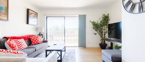 A modern living room with a sofa, ottoman, coffee table, and a TV.