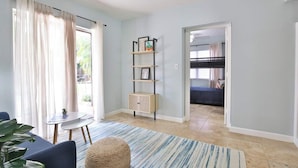 A modern room with a sofa, a small table, a bookshelf, and a bunk bed.
