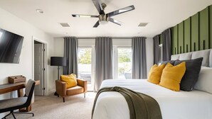 Une chambre d’hôtel équipée d’un lit, d’un bureau, d’une chaise, d’un ventilateur de plafond et d’une télévision.