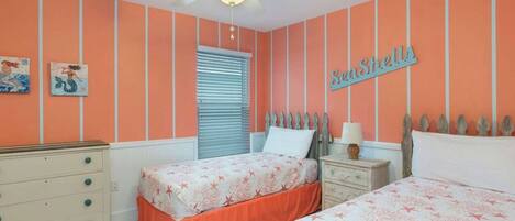 A bedroom with two beds, a dresser, a ceiling fan, and a window with blinds.