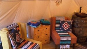 Ein gemütliches Interieur mit einem gelben Sessel, einer Holzkommode und einem gemusterten Teppich.