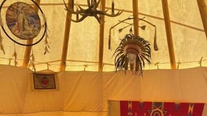 Ein gemütliches Interieur mit einem Bett, einem Tisch mit verschiedenen Gegenständen und einem hängenden Traumfänger.