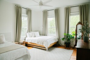 A bedroom with a bed, bedside tables, a mirror, and a potted plant. - Historic 5/4 • Spacious • Sleeps 16 • Hot Tub • Pool • A&M (Bryan)