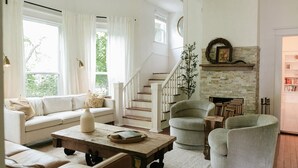 A spacious living room with a sofa, armchairs, a coffee table, and a fireplace. - Historic 5/4 • Spacious • Sleeps 16 • Hot Tub • Pool • A&M (Bryan)
