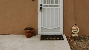 A house with a white door, a number '2830' on the wall, a potted plant, a doormat, and a sign with 'A-TECH' and a phone number. - University District Guesthouse-Minutes to Nob Hill (Albuquerque)