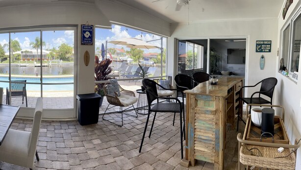 Ein Zimmer mit Blick auf einen Pool, eine Essecke mit Stühlen und einem Tisch sowie ein Hinweis zur Vorbereitung auf Hurrikane.