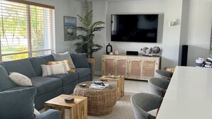 Ein modernes Wohnzimmer mit grauem Sofa, Couchtisch und Fernseher.