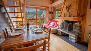 Ein Holzesstisch mit Stühlen, ein Sofa und ein Kamin mit Steinverkleidung.