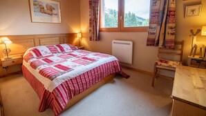 Ein gemütliches Schlafzimmer mit einem großen Bett, einem Nachttisch, einem Sessel und einem Fenster mit Vorhängen.