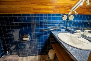 Ein Badezimmer mit blauen Fliesen, einer Holzboden und einem Waschbecken sowie einem Spiegel.