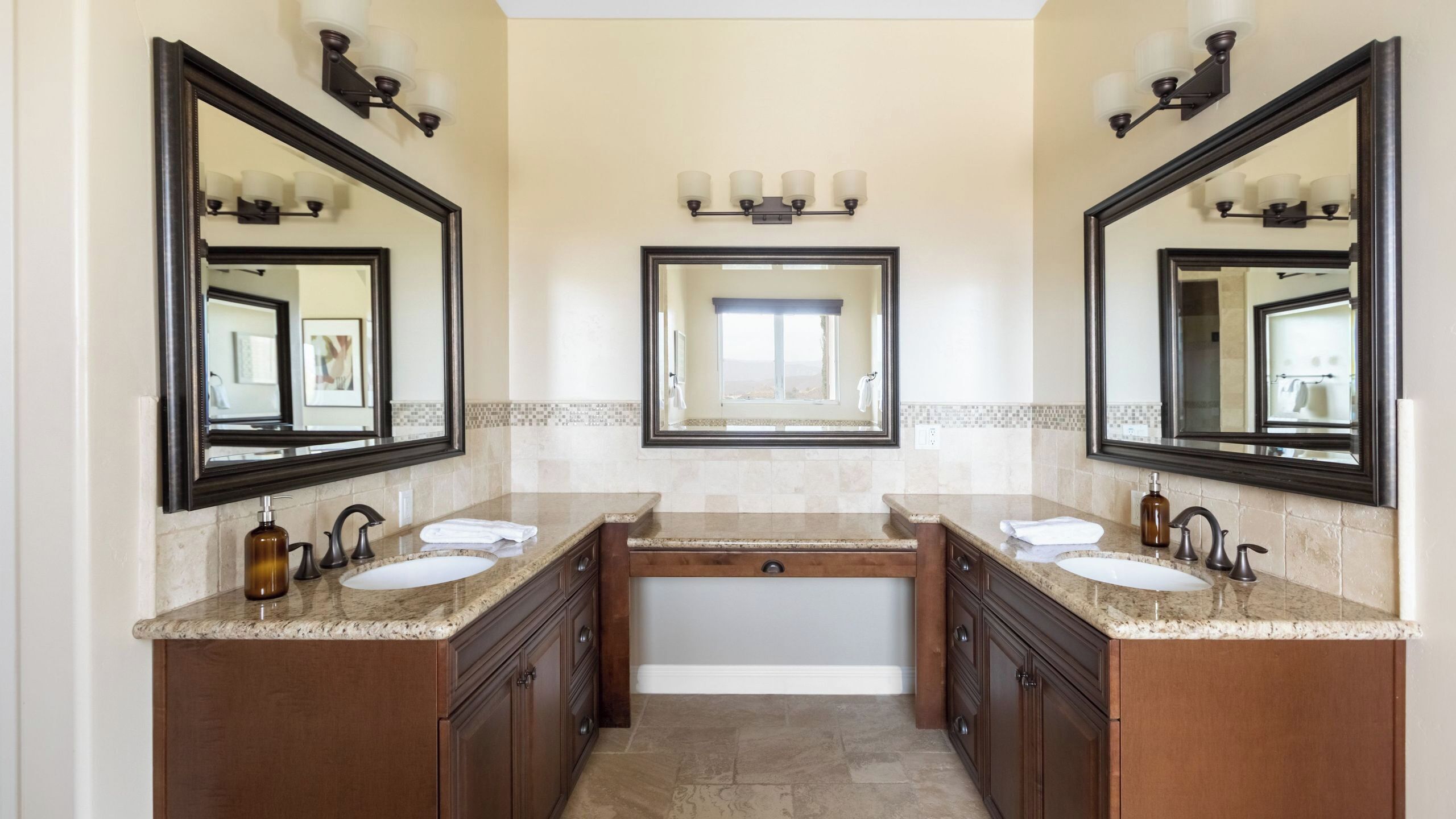 A bathroom with two sinks, a large mirror, and a vanity with a towel rack.