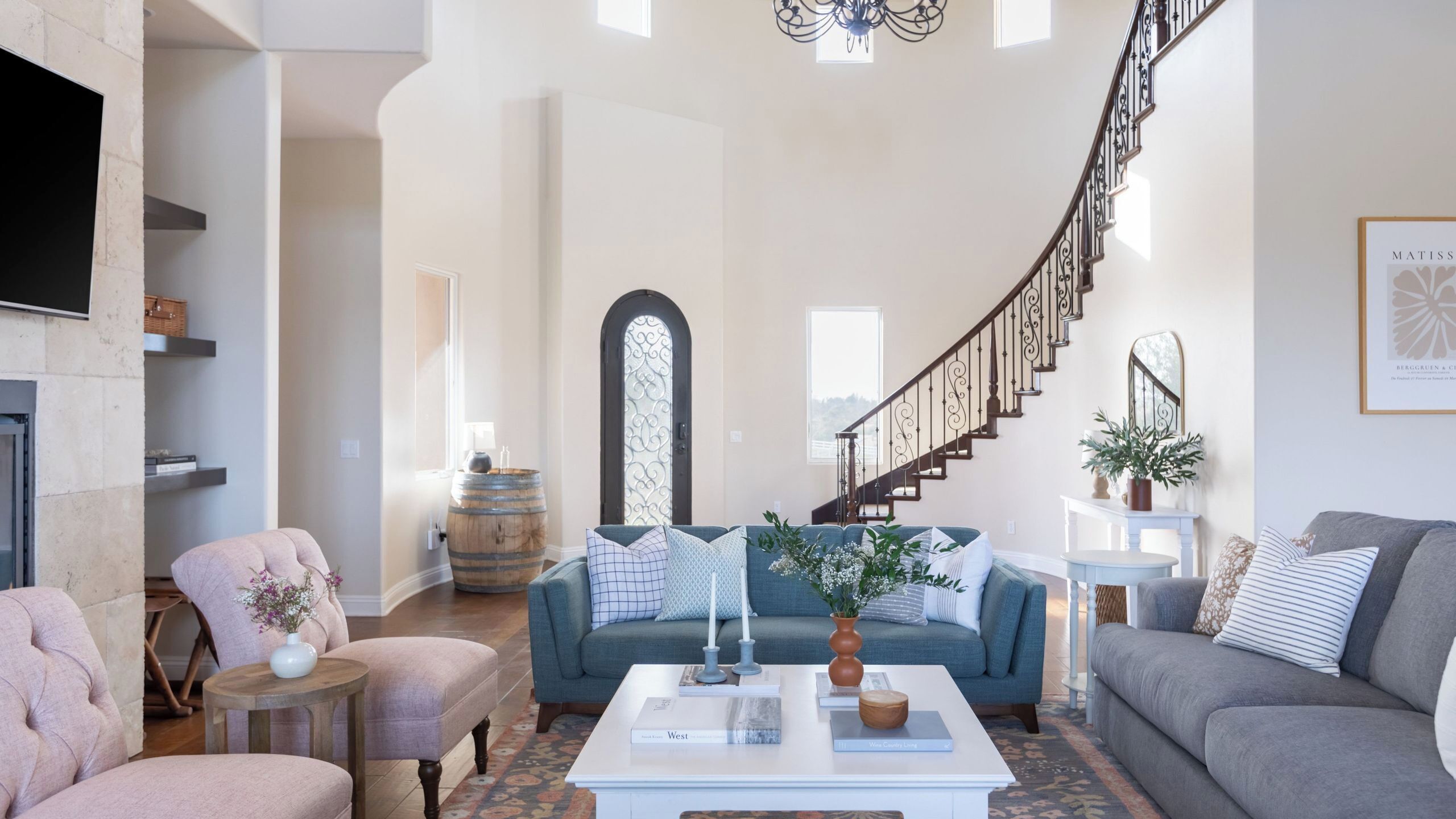 A spacious living room with a fireplace, a staircase, and a large window.