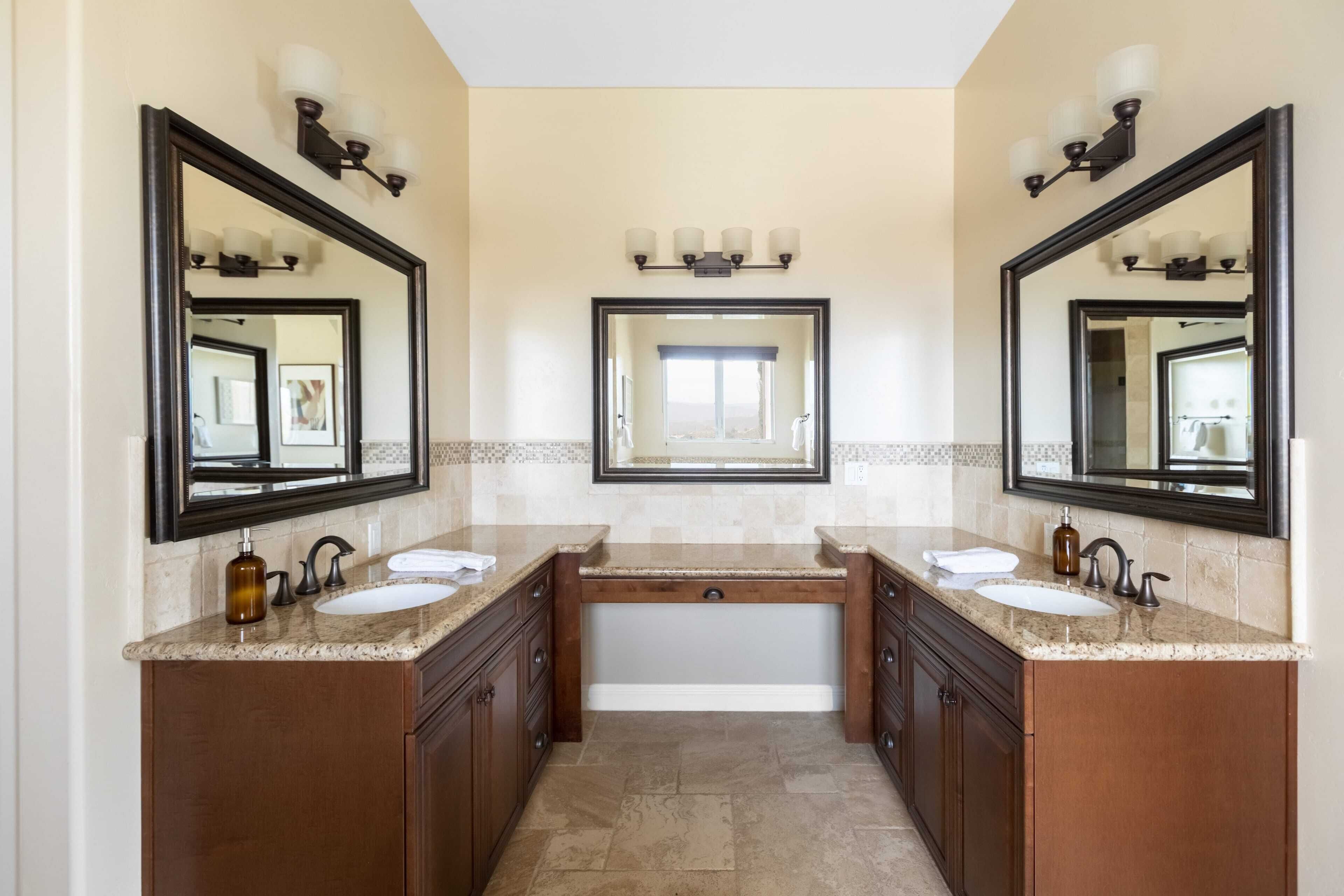 Une salle de bain avec deux lavabos, un grand miroir et une baignoire.