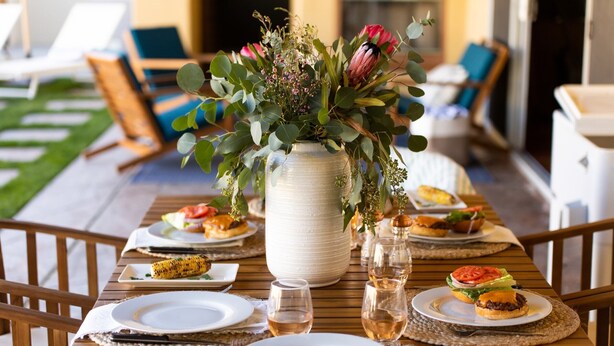 A dining table set with plates, glasses, and a centerpiece of flowers. - Amarilla by Avantstay Peaceful Paradise w/ Pool, Spa & Theatre Room (La Quinta)