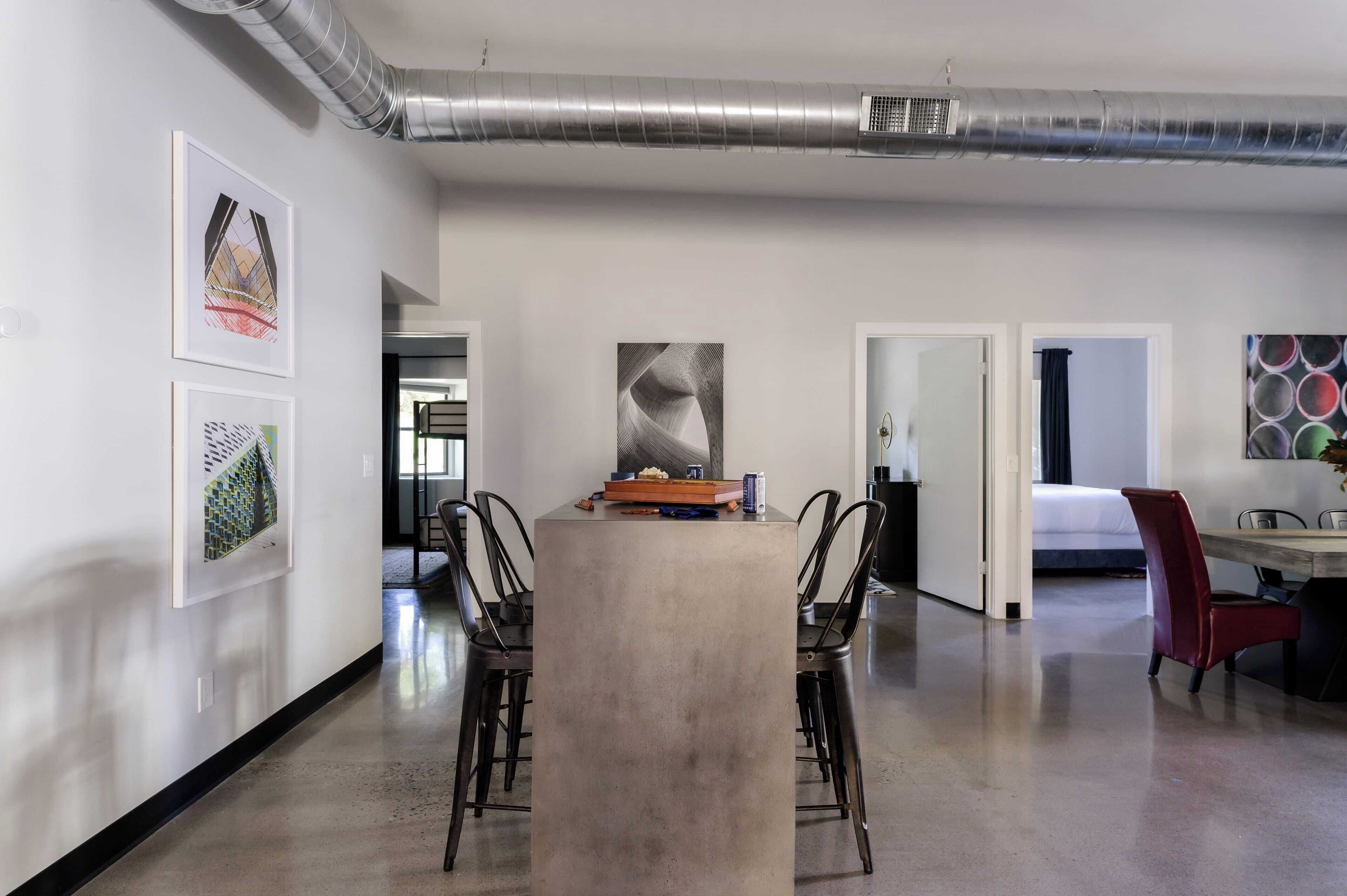 A modern interior with a central table, chairs, and artwork on the walls.