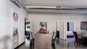 Ein modernes Interieur mit einem zentralen Tisch, Stühlen und Kunstwerken an den Wänden.