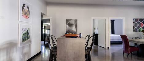 A modern interior with a central table, chairs, and artwork on the walls.