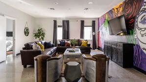 Ein modernes Wohnzimmer mit einer Eckcouch, zwei Sesseln, einem Couchtisch und einem Fernseher auf einem Lowboard.