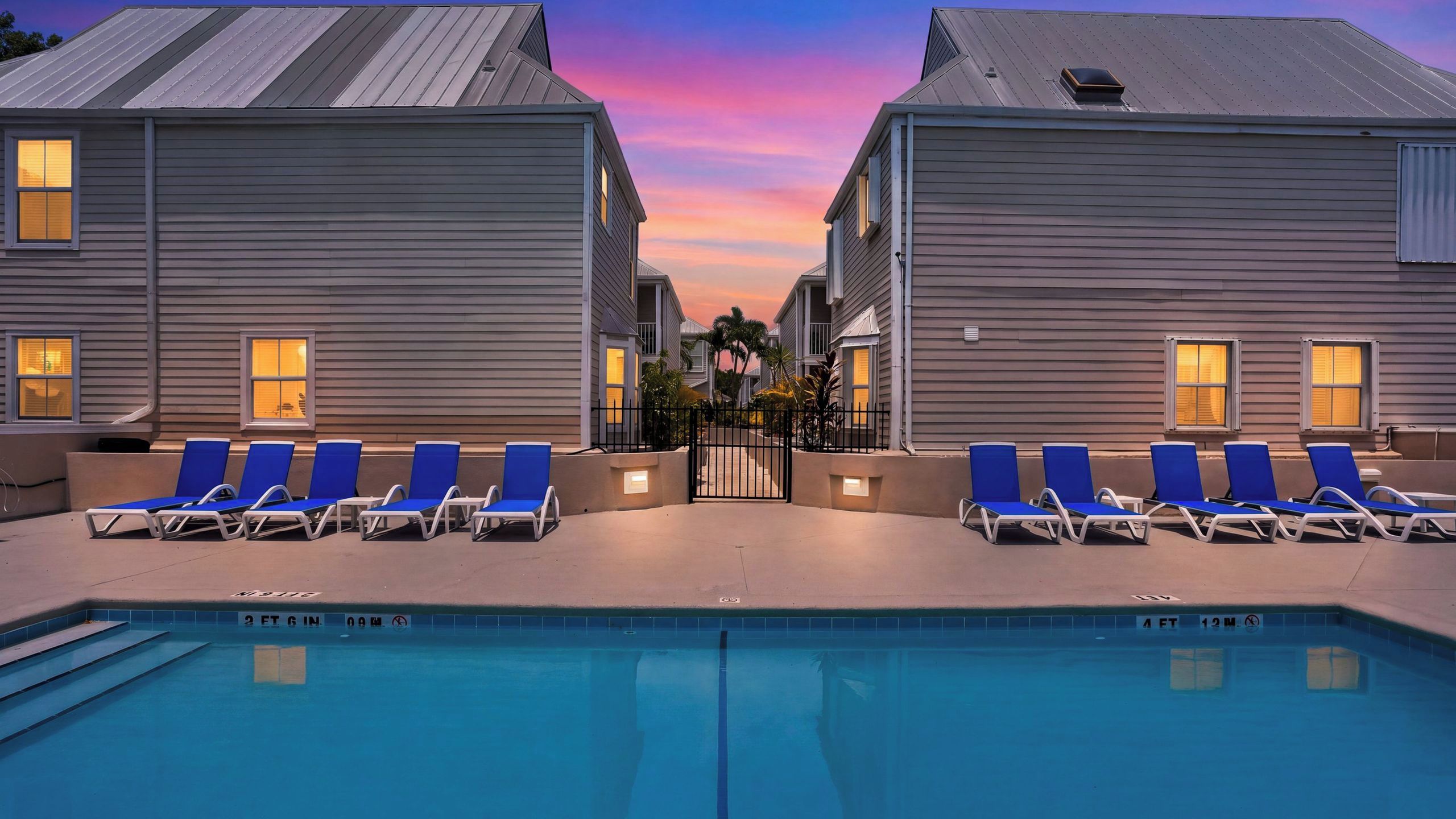 A swimming pool with lounge chairs and a sunset sky.