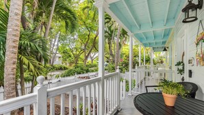 A covered outdoor area with a white picket fence, a black table, and a potted plant. - Southard Getaway by Avantstay w/ Covered Patio, Great Location & Shared Pool! Month Long Stays (Key West)