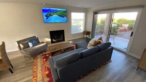A living room with a large TV, a sofa, a coffee table, and a patterned rug.