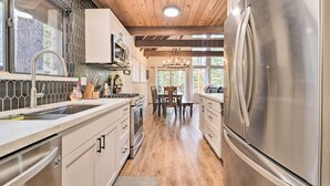 A modern kitchen with stainless steel appliances, wooden ceiling beams, and a view of the outdoors. - 2 Mi to Tahoe Donner Ski Resort: Forest-View Haven (Truckee)