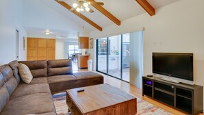 A modern living room with a sectional sofa, a wooden coffee table, a flat-screen TV on a wooden stand, and a ceiling fan. - Fort Myers Home, Lanai & Private, Heated Pool (Fort Myers)