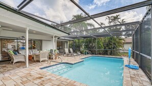A covered swimming pool with lounge chairs and a patio area. - Fort Myers Home, Lanai & Private, Heated Pool (Fort Myers)