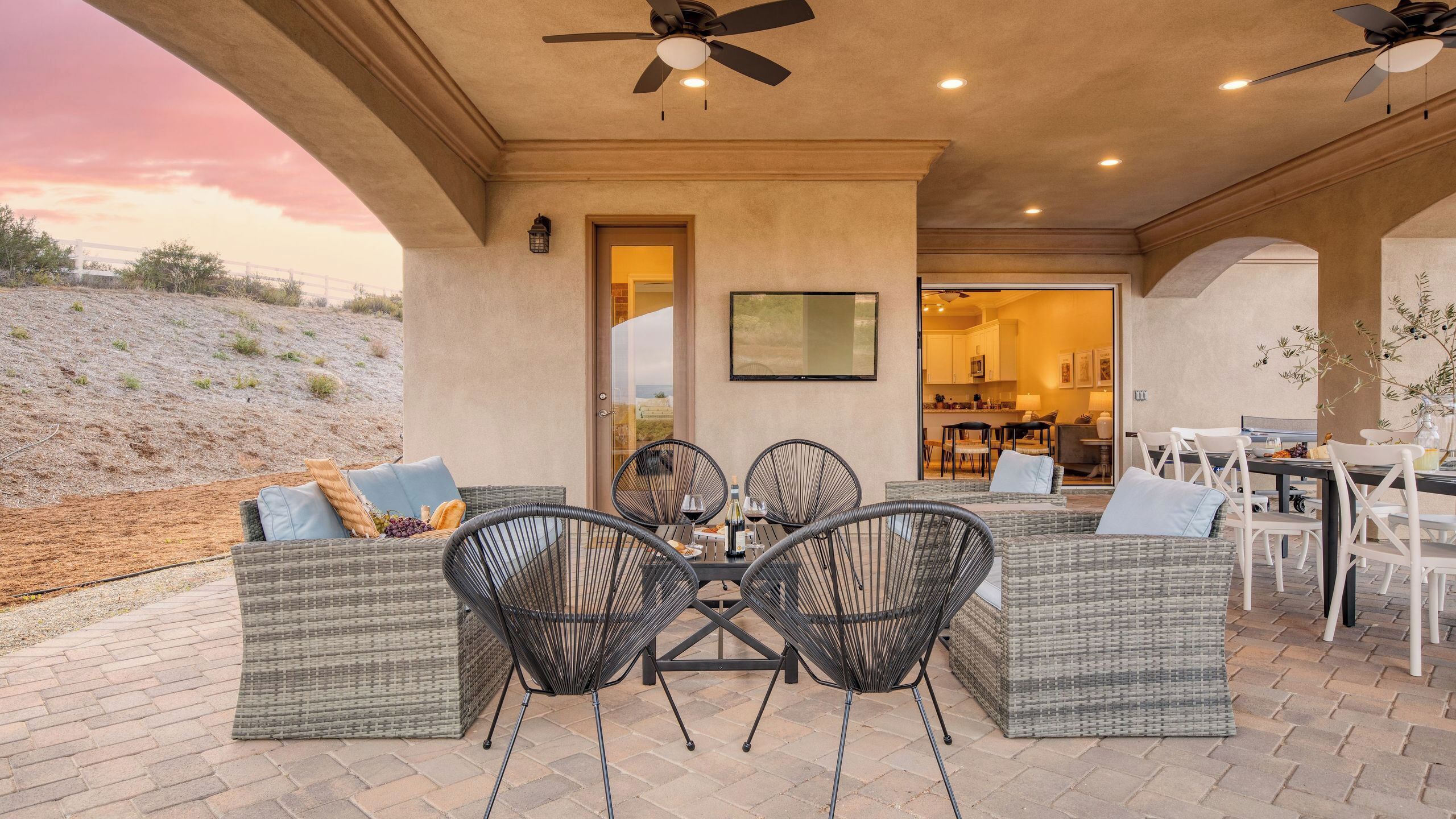 An outdoor patio with wicker furniture, a ceiling fan, and a view of the landscape.