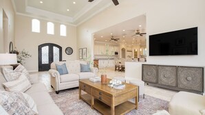 A spacious living room with a sofa, coffee table, and a TV mounted on the wall.