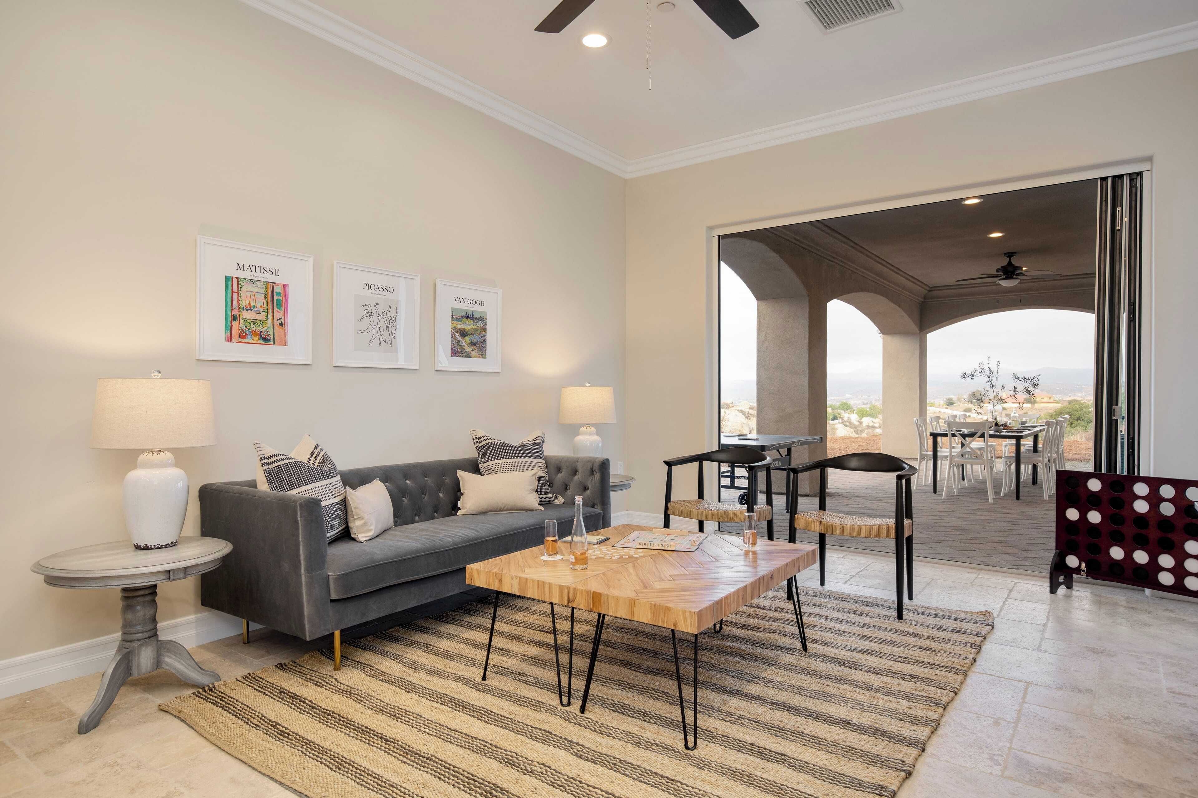 A living room with a grey sofa, a wooden coffee table, and a view of an outdoor patio.