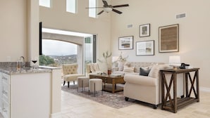 A spacious living area with a sofa, coffee table, and a view through a large window.