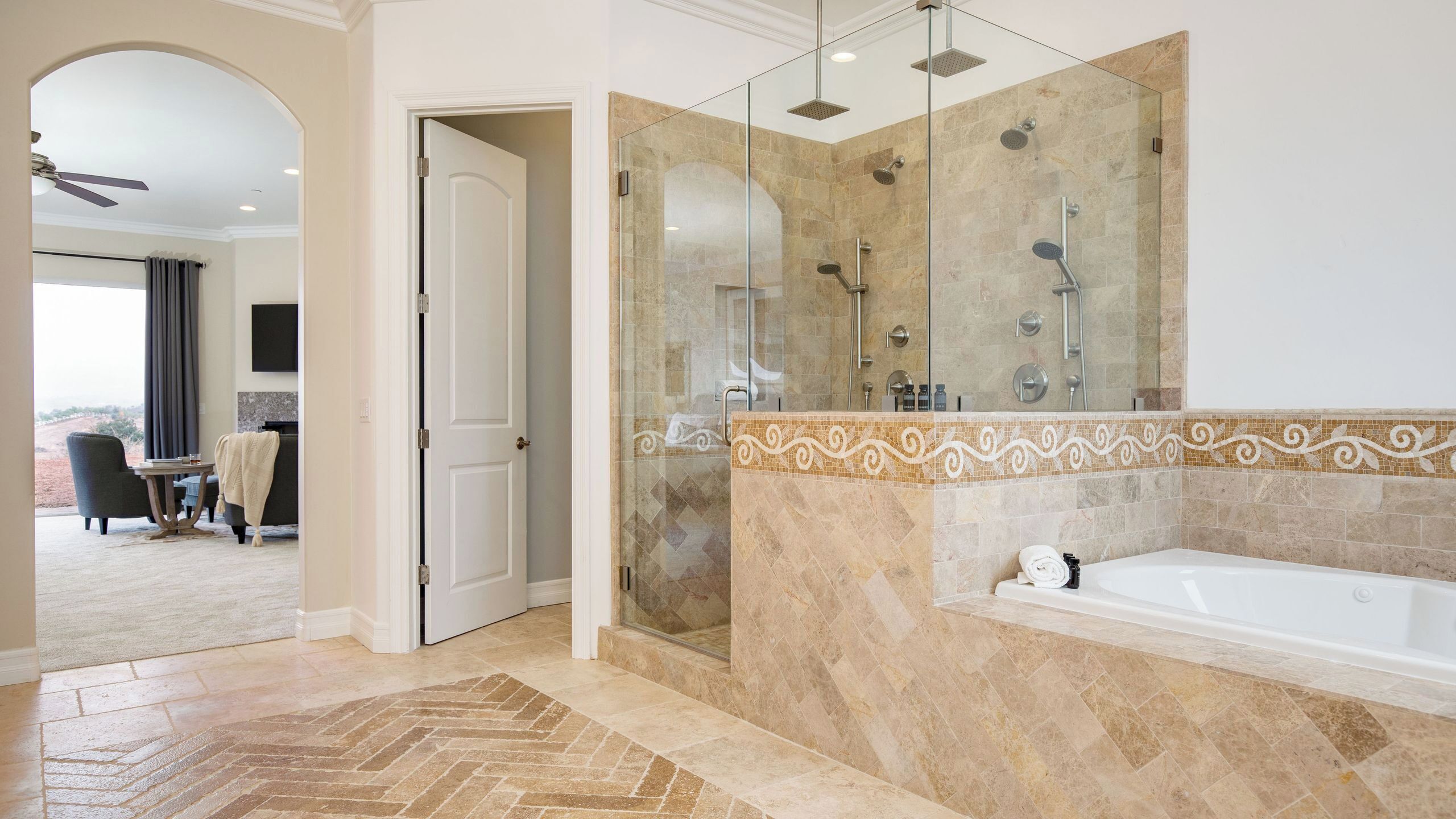A modern bathroom with a glass-enclosed shower, a large bathtub, and a herringbone-patterned floor.
