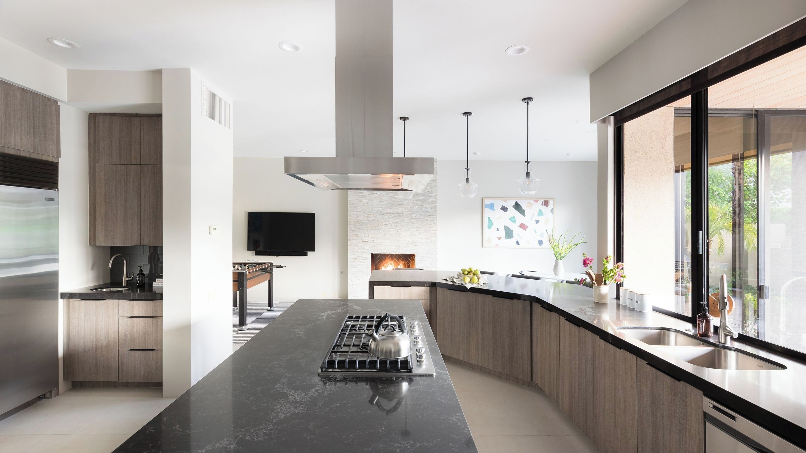 A modern kitchen with a central island, stainless steel appliances, and a large window providing a view.