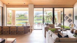 A spacious living area with a large sliding glass door leading to a poolside area, featuring a sofa, dining chairs, and a coffee table.