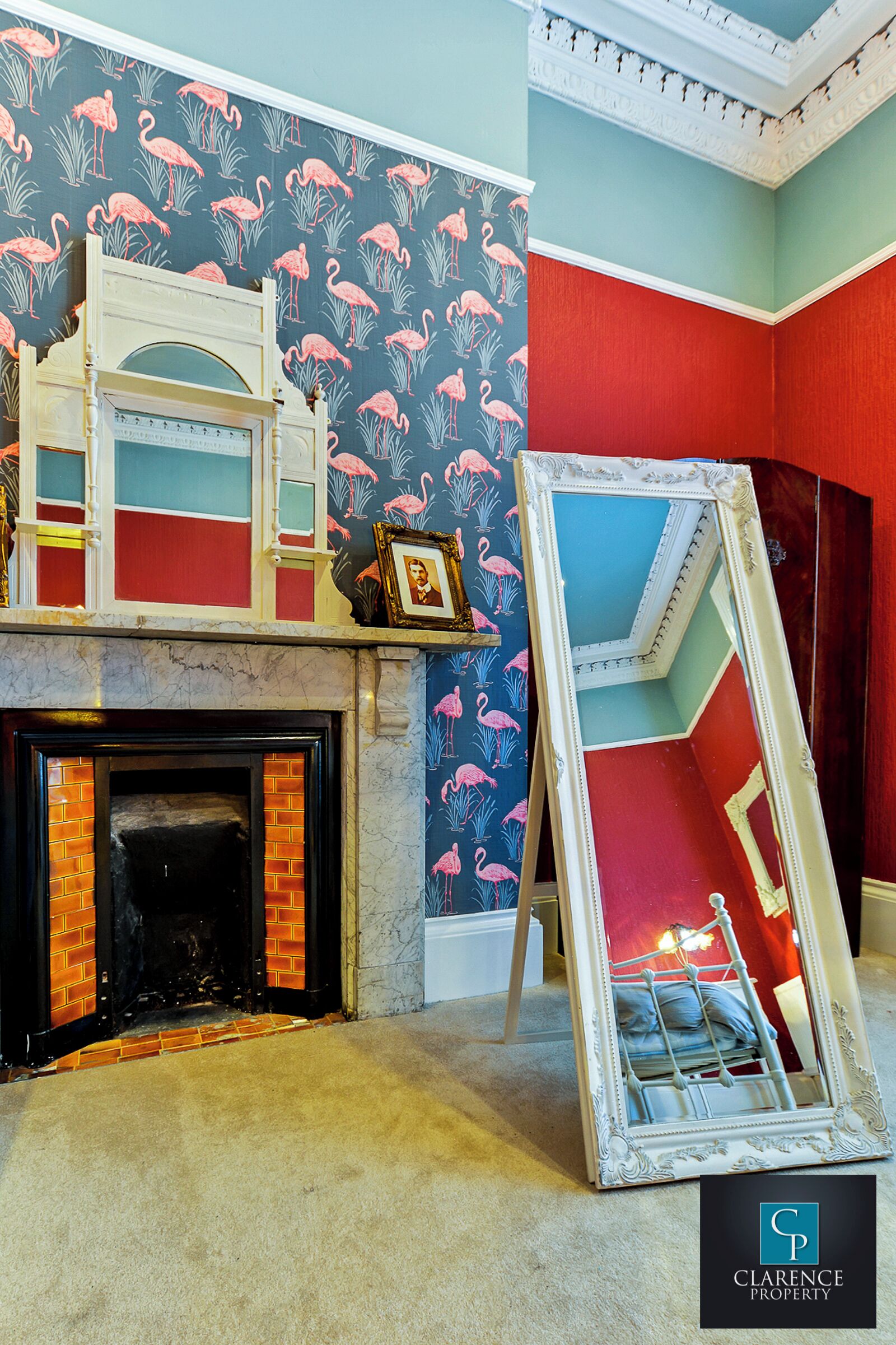 A room with a fireplace, a mirror, and a wall with a flamingo pattern.