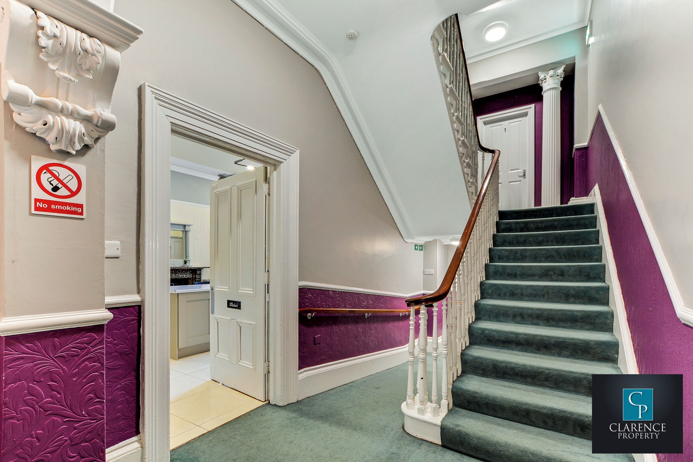 A staircase with a purple wall and white trim, leading to a room with a white door and a "No Smoking" sign.