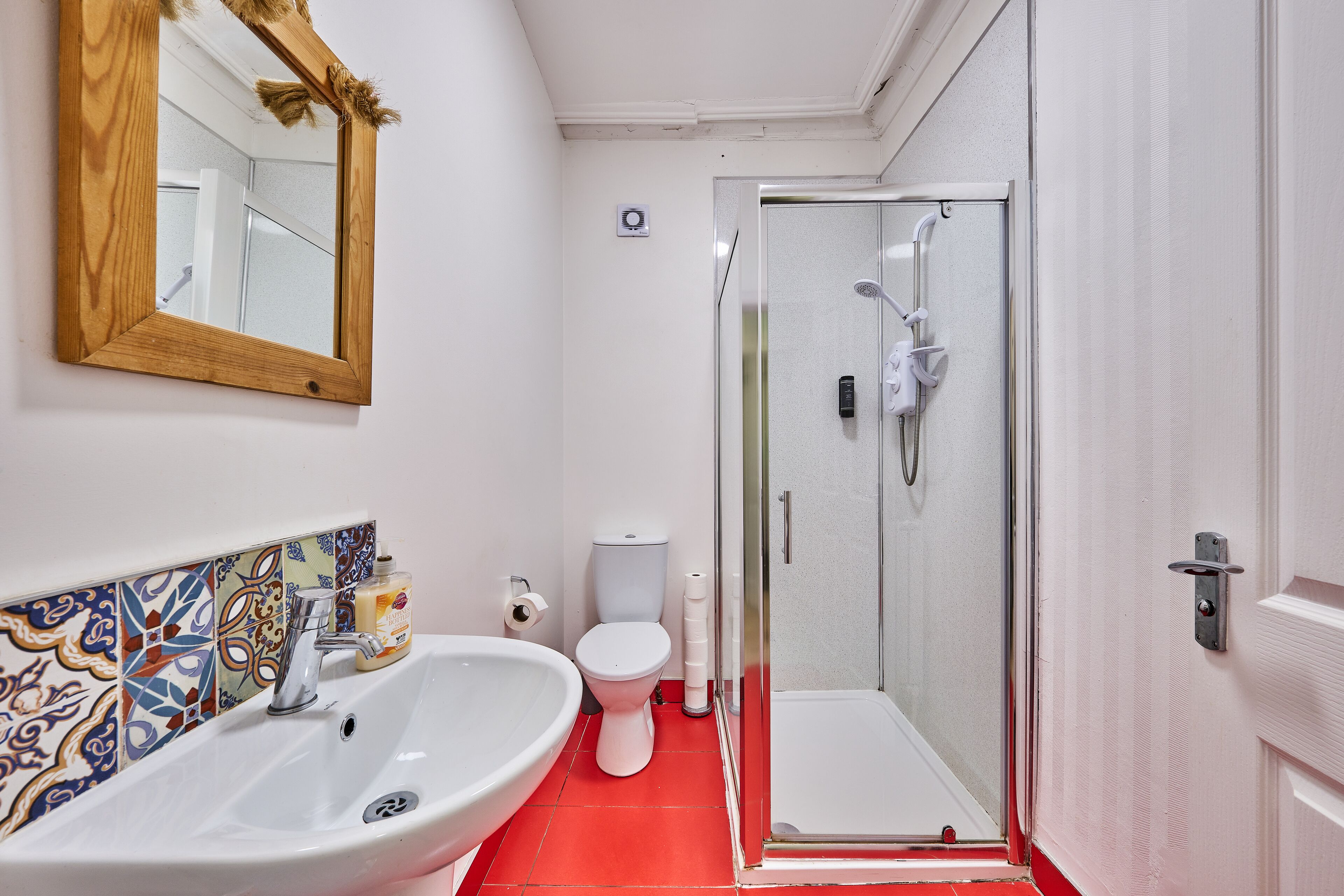 Un baño con lavamanos blanco, inodoro y cabina de ducha de cristal.