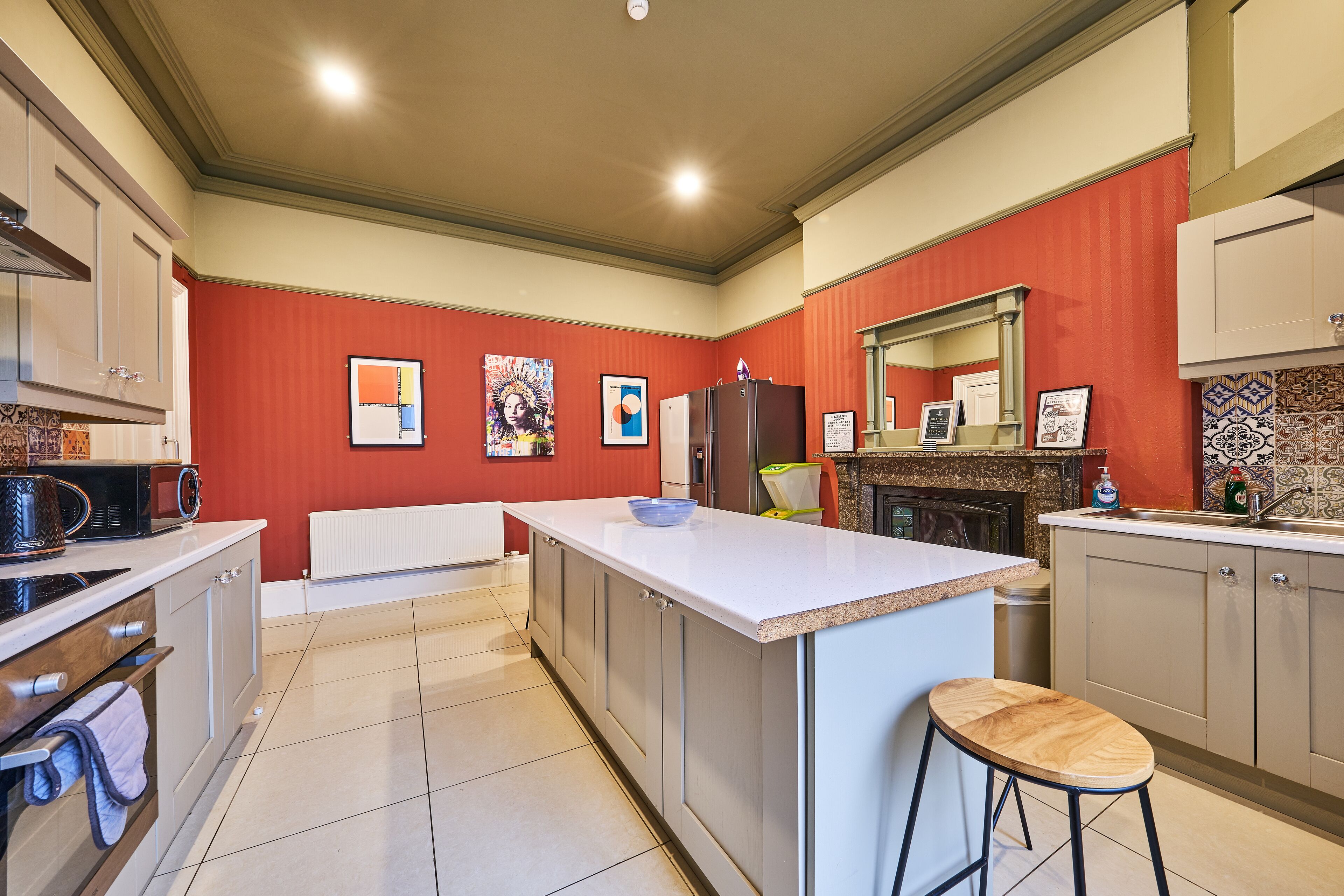 A kitchen with a central island, white cabinets, and a red accent wall.