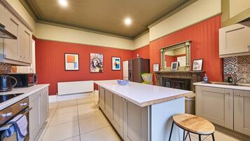 A kitchen with a central island, white cabinets, and a red accent wall.