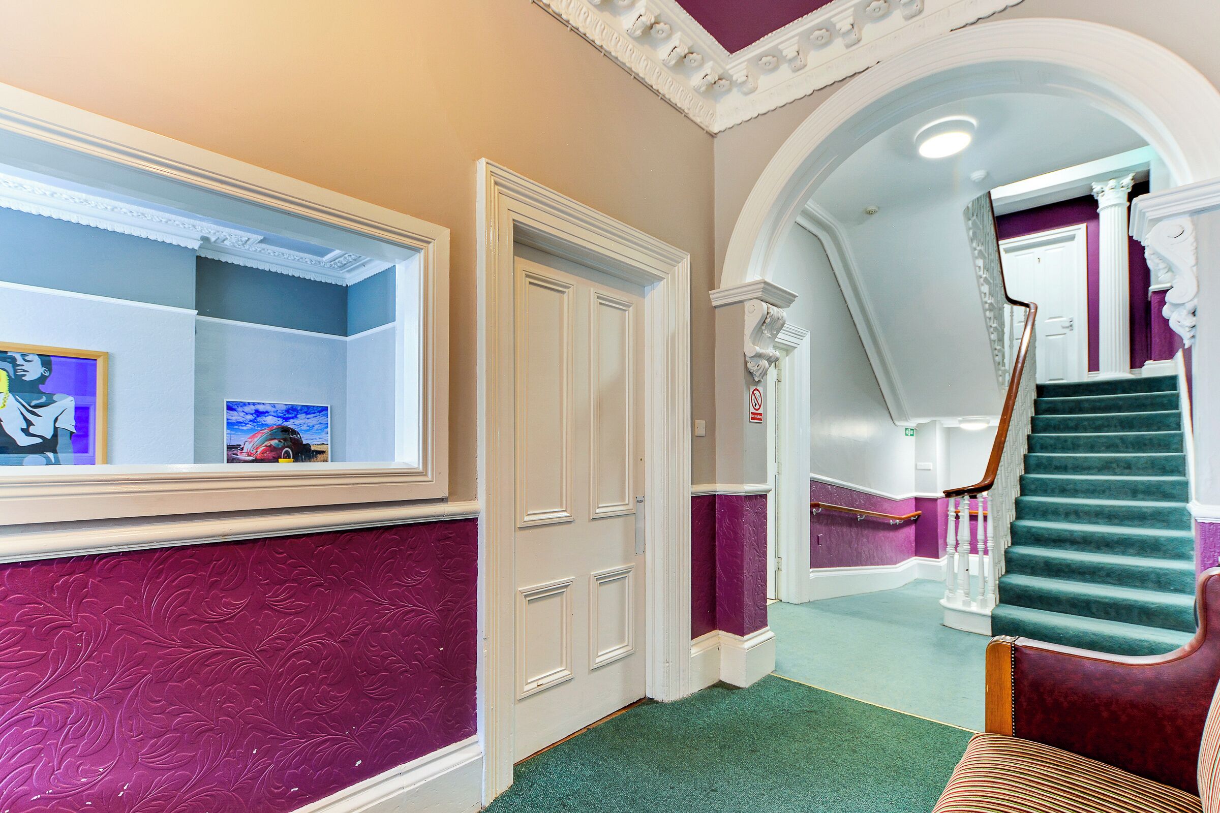 A hallway with a mirror, a door, and a staircase.