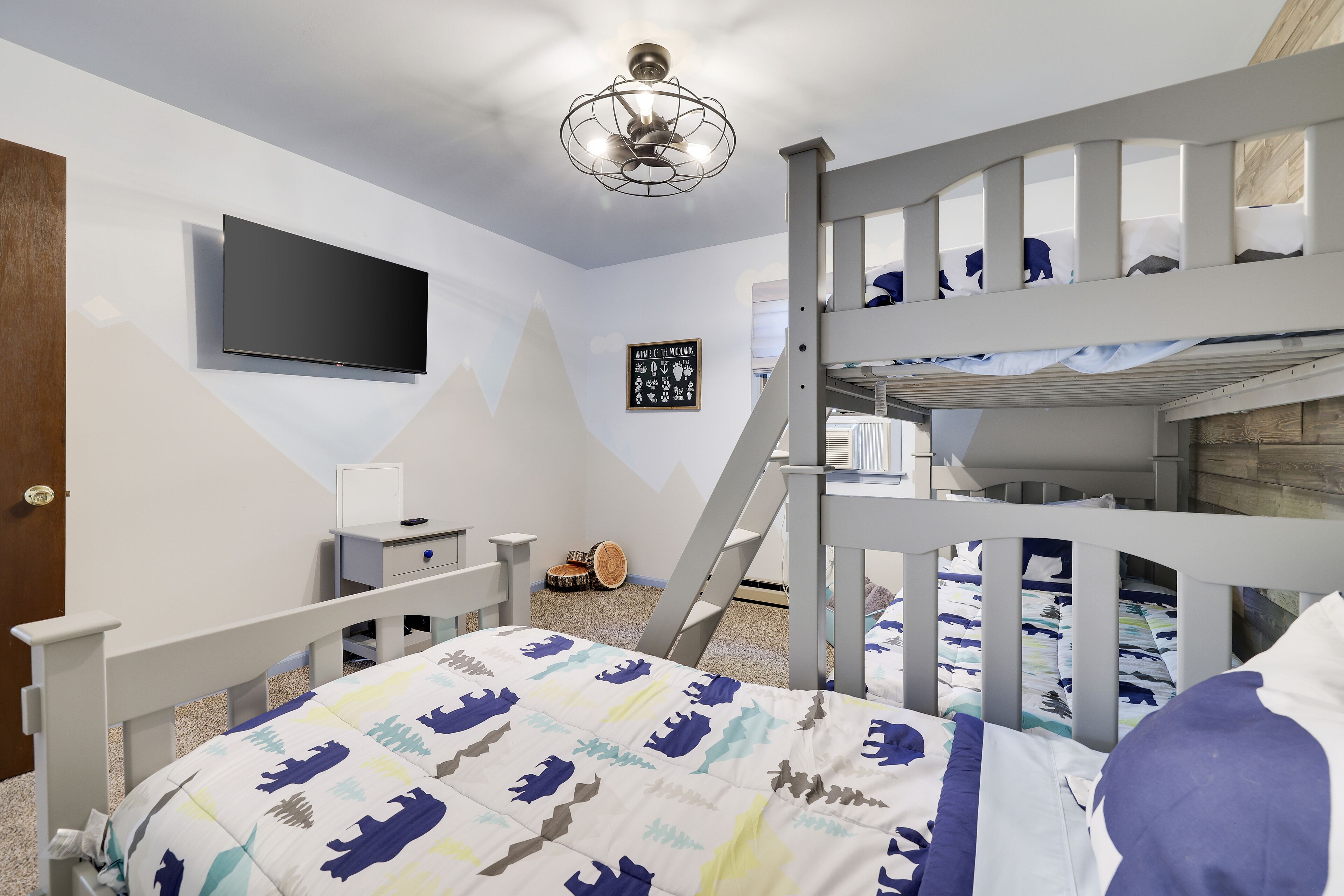A bedroom with bunk beds, a flat-screen TV, a desk, and a chair.
