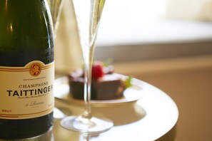 Champagne en een glas op een tafel, met een dessert op de achtergrond.