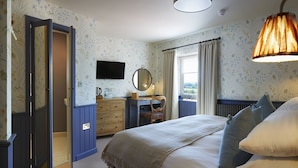 A bedroom with a bed, a dresser, a mirror, and a window with curtains. - The Grainary Boutique Hotel (Scarborough)