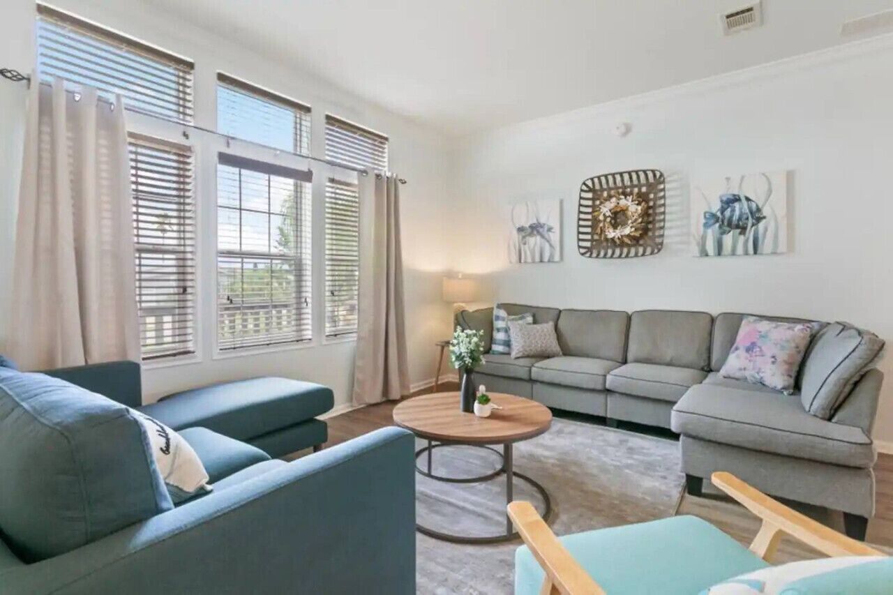 A living room with a grey sofa, a blue armchair, a round wooden coffee table, and a grey couch.