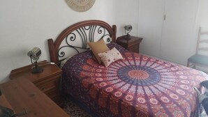 Un dormitorio con cama, cabecero de madera, mesitas de noche y un adorno en la pared.
